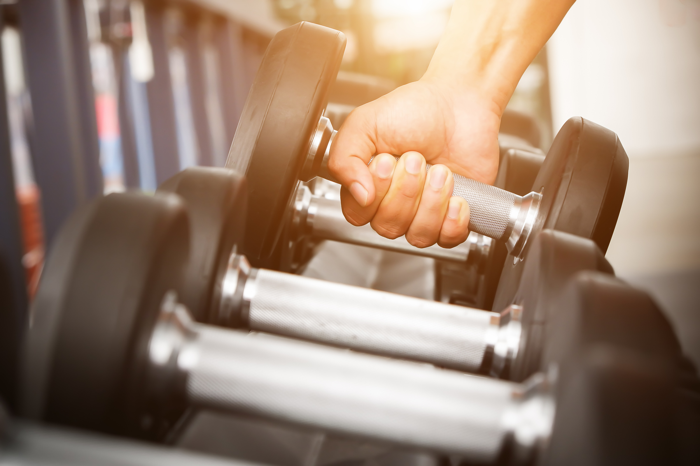 Hand Taking a Dumbbell from the Rack in the Gym